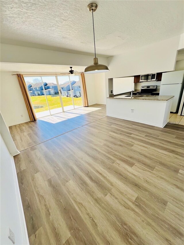 658 Caribbean Dr, Davenport, FL 33897 - unfurnished living room featuring light wood-style floors, a textured ceiling, and a sink