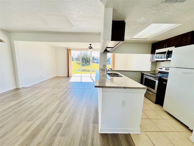 658 Caribbean Dr, Davenport, FL 33897 - kitchen featuring stainless steel appliances, a sink, a textured ceiling, light stone countertops, and a peninsula
