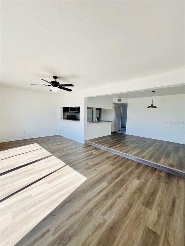 658 Caribbean Dr, Davenport, FL 33897 - unfurnished living room with wood finished floors, ceiling fan, and a sink