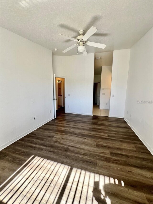 658 Caribbean Dr, Davenport, FL 33897 - unfurnished bedroom featuring wood finished floors, a textured ceiling, baseboards, a ceiling fan, and ensuite bath