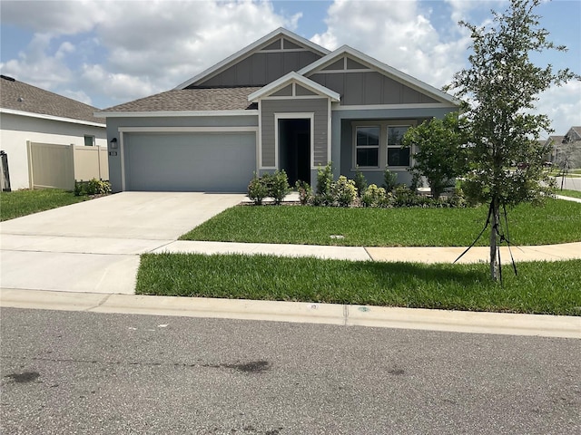 553 SE Turtle, Haines City, FL 33844 - view of front facade featuring an attached garage, concrete driveway, a front lawn, and board and batten siding