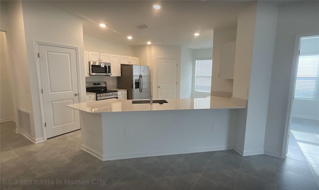 553 SE Turtle, Haines City, FL 33844 - kitchen with appliances with stainless steel finishes, a sink, white cabinetry, a peninsula, and baseboards