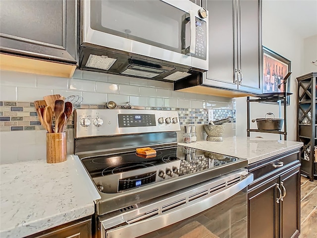 605 San Augusto Dr, Kissimmee, FL 34759 - kitchen featuring stainless steel appliances, decorative backsplash, light stone countertops, and dark brown cabinetry
