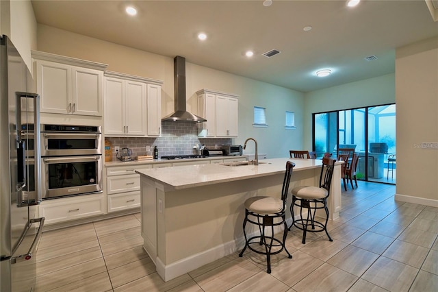 14553 Eagle Branch Dr, Nokomis, FL 34275 - kitchen with wall chimney exhaust hood, appliances with stainless steel finishes, a sink, a kitchen island with sink, and tasteful backsplash