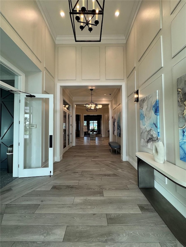14553 Eagle Branch Dr, Nokomis, FL 34275 - hallway featuring a chandelier, ornamental molding, a decorative wall, a towering ceiling, and wood finished floors