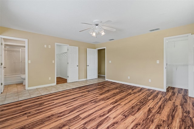11323 Kijik Trl, Groveland, FL 34736 - unfurnished bedroom featuring a walk in closet, a closet, wood finished floors, ensuite bathroom, and a ceiling fan
