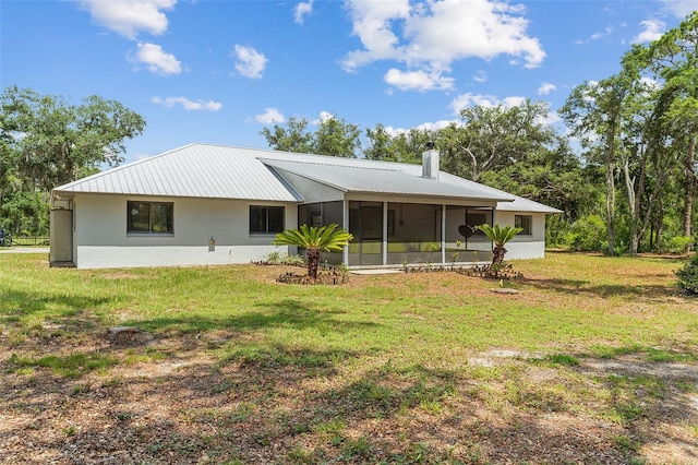 11323 Kijik Trl, Groveland, FL 34736 - back of property featuring a sunroom, a yard, a metal roof, a chimney, and stucco siding