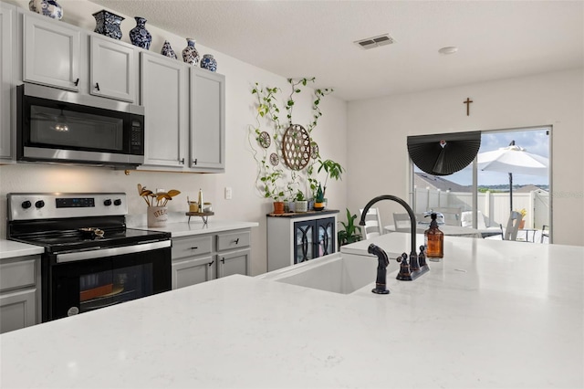 176 Sofia Ln, Lake Alfred, FL 33850 - kitchen with appliances with stainless steel finishes, a sink, gray cabinetry, and light stone countertops