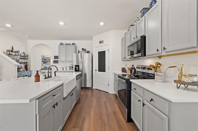 176 Sofia Ln, Lake Alfred, FL 33850 - kitchen featuring stainless steel appliances, a sink, dark wood-style flooring, light countertops, and arched walkways