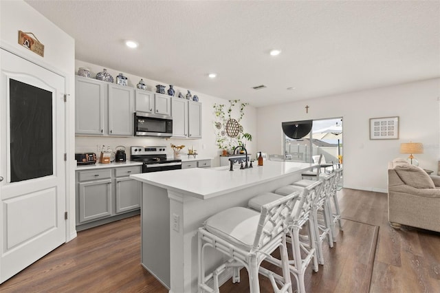 176 Sofia Ln, Lake Alfred, FL 33850 - kitchen featuring stainless steel appliances, gray cabinets, dark wood-type flooring, light countertops, and a breakfast bar area