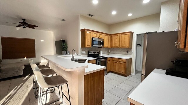 3901 Ballinore Pl, Gotha, FL 34734 - kitchen featuring appliances with stainless steel finishes, a peninsula, light tile patterned floors, a kitchen bar, and open floor plan