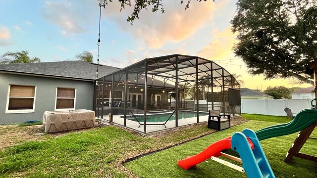 3901 Ballinore Pl, Gotha, FL 34734 - rear view of house featuring a playground, a shingled roof, glass enclosure, stucco siding, and a patio area