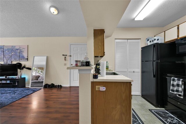 1025 S Hiawassee Rd Unit 2225, Orlando, FL 32835 - kitchen featuring black appliances, a textured ceiling, open floor plan, light countertops, and a peninsula