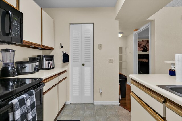 1025 S Hiawassee Rd Unit 2225, Orlando, FL 32835 - kitchen featuring black appliances, light countertops, white cabinets, and light tile patterned floors
