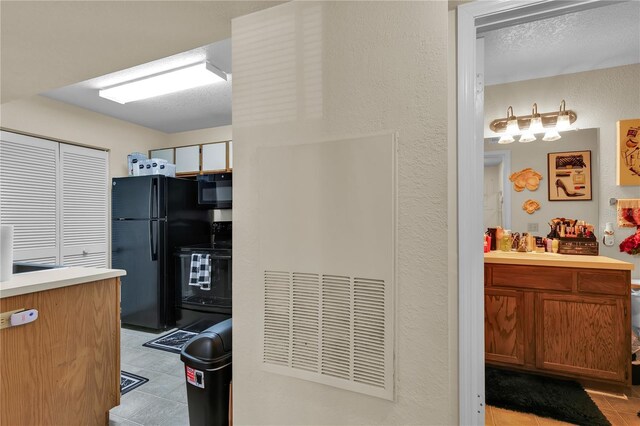 1025 S Hiawassee Rd Unit 2225, Orlando, FL 32835 - kitchen with black appliances, light tile patterned floors, light countertops, a sink, and a textured wall