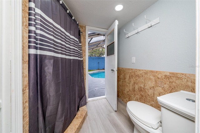 5015 Nassau Cir Unit 4, Orlando, FL 32808 - full bath with tile walls, wood finished floors, wainscoting, toilet, and a shower with shower curtain