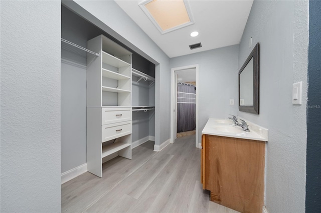 5015 Nassau Cir Unit 4, Orlando, FL 32808 - bathroom with double vanity, wood finished floors, baseboards, a textured wall, and a spacious closet