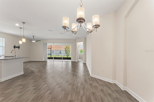 1101 Downswing Pl, Davenport, FL 33896 - unfurnished living room with dark wood-style flooring, baseboards, ceiling fan, and a chandelier