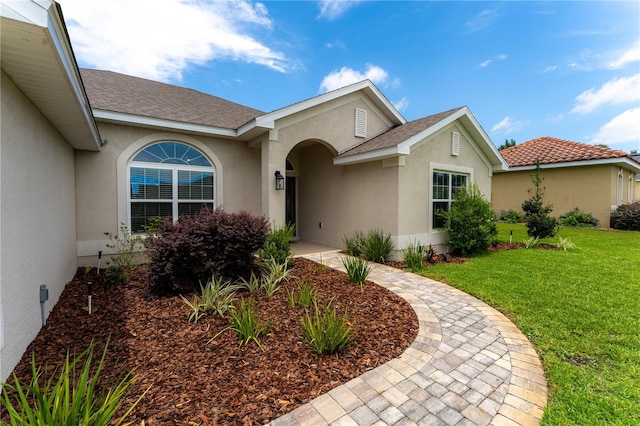 6644 SW 179th Court Rd, Dunnellon, FL 34432 - doorway to property featuring stucco siding, a yard, and roof with shingles