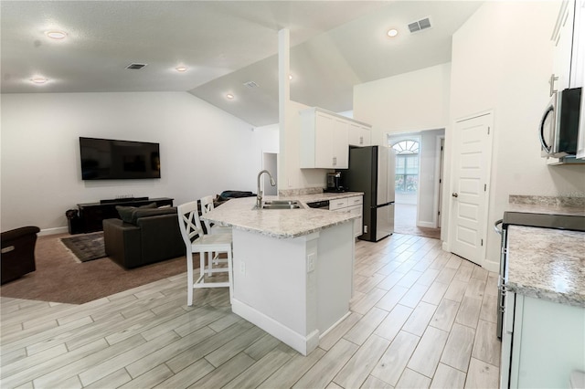 6644 SW 179th Court Rd, Dunnellon, FL 34432 - kitchen with open floor plan, appliances with stainless steel finishes, a peninsula, lofted ceiling, and white cabinets