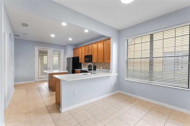 13636 Beauregard Pl, Orlando, FL 32837 - kitchen with black microwave, light countertops, refrigerator with ice dispenser, light tile patterned floors, and recessed lighting