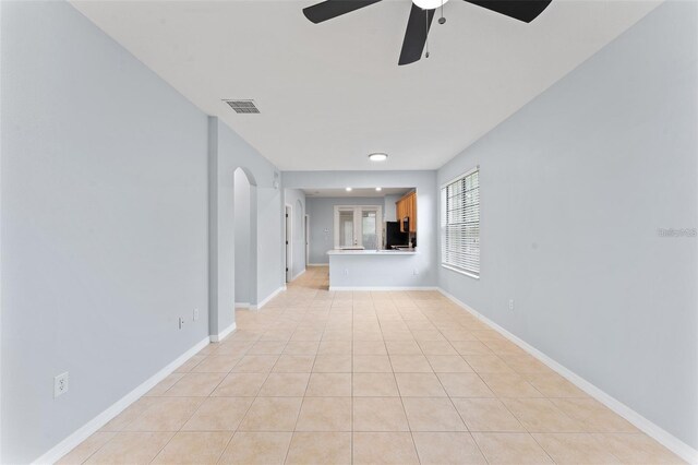 13636 Beauregard Pl, Orlando, FL 32837 - unfurnished living room with a ceiling fan, light tile patterned flooring, arched walkways, and baseboards