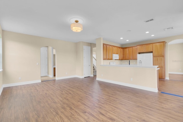 2255 Stone Lake Ct, Orlando, FL 32824 - kitchen with arched walkways, white appliances, open floor plan, light wood-style flooring, and recessed lighting
