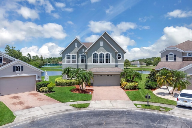 2255 Stone Lake Ct, Orlando, FL 32824 - traditional-style house with decorative driveway, stucco siding, a front lawn, a water view, and an attached garage