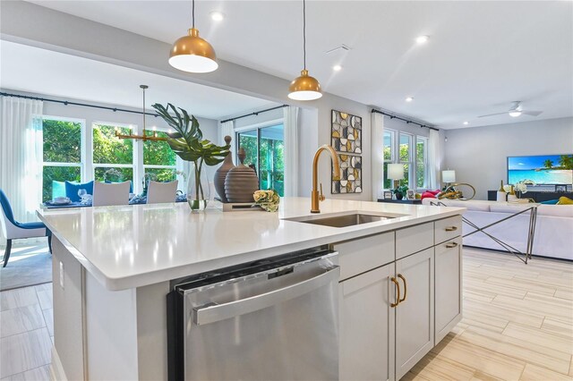 217 Thornberry Way, Palm Coast, FL 32164 - kitchen featuring stainless steel dishwasher, a sink, open floor plan, a kitchen island with sink, and light countertops