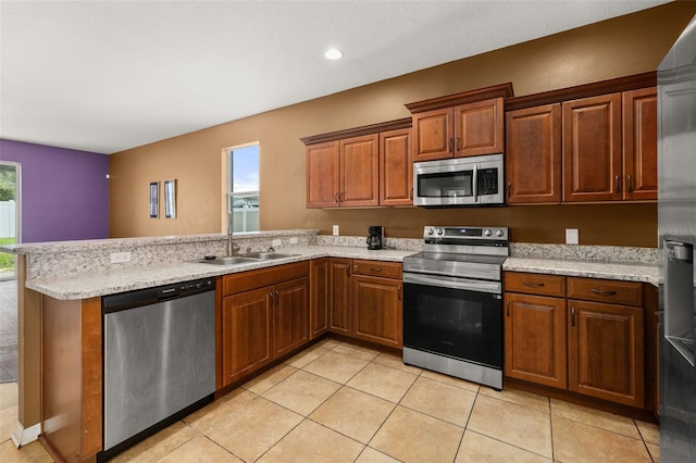 326 Highland Meadows Ave, Davenport, FL 33837 - kitchen with appliances with stainless steel finishes, a sink, a peninsula, light tile patterned floors, and brown cabinetry