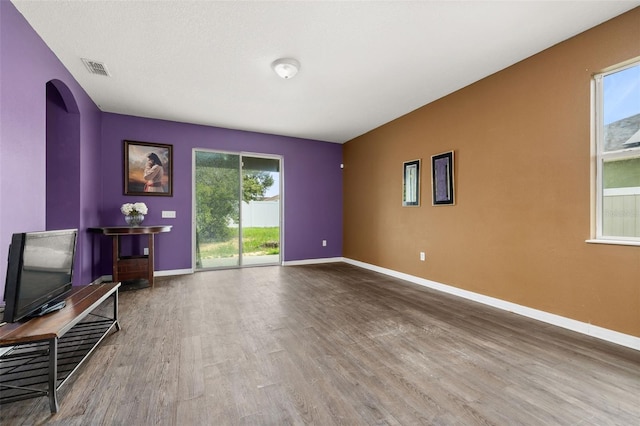 326 Highland Meadows Ave, Davenport, FL 33837 - unfurnished living room featuring wood finished floors, baseboards, and arched walkways