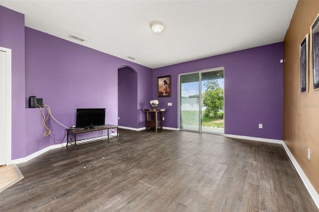 326 Highland Meadows Ave, Davenport, FL 33837 - unfurnished living room featuring arched walkways, wood finished floors, and baseboards