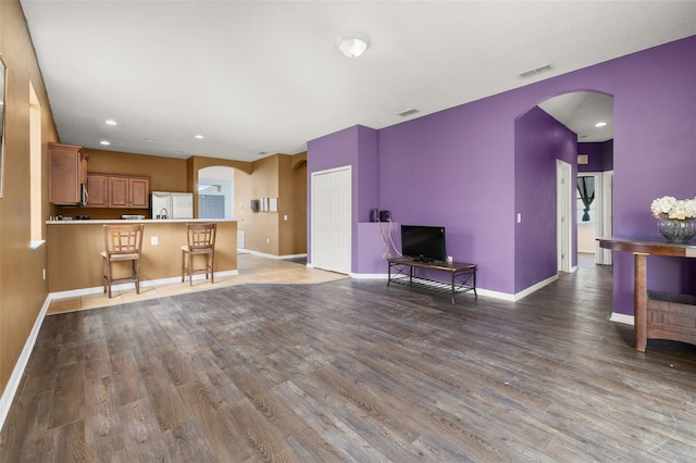 326 Highland Meadows Ave, Davenport, FL 33837 - unfurnished living room featuring arched walkways, wood finished floors, baseboards, and recessed lighting