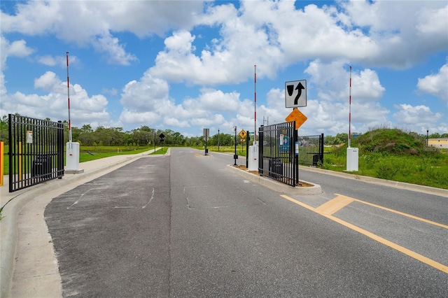 1335 Greenfield Loop, Kissimmee, FL 34747 - view of asphalt street featuring traffic signs, curbs, and a gated entry