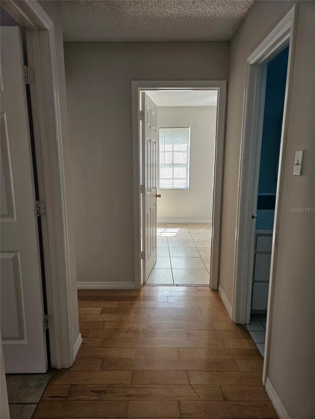 2805 Rodeo Dr, Kissimmee, FL 34746 - hall featuring light wood-style floors, a textured ceiling, and baseboards
