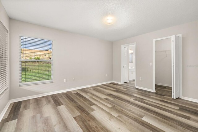 2146 Fish Eagle St, Clermont, FL 34714 - unfurnished bedroom featuring wood finished floors, baseboards, ensuite bathroom, and a spacious closet