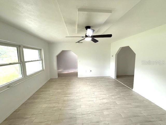 5249 SE 106th Ln, Belleview, FL 34420 - empty room with ceiling fan, arched walkways, and light wood finished floors