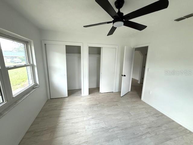 5249 SE 106th Ln, Belleview, FL 34420 - unfurnished bedroom featuring multiple closets, light wood-style floors, ceiling fan, and baseboards