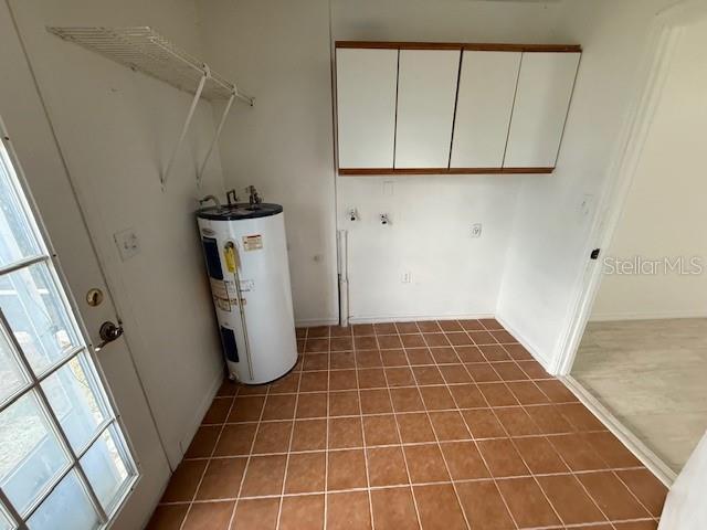 5249 SE 106th Ln, Belleview, FL 34420 - laundry room with electric water heater, tile patterned flooring, cabinet space, and baseboards