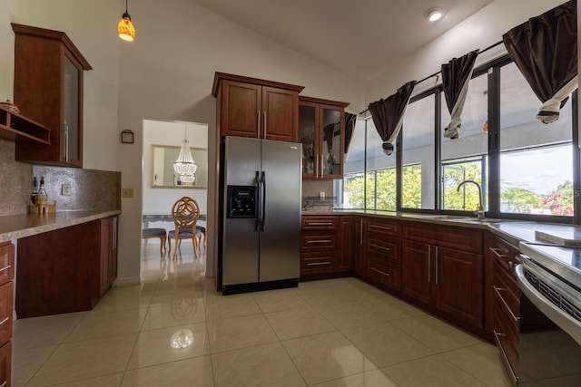 121 White Birch Dr, Kissimmee, FL 34743 - kitchen featuring stainless steel fridge, backsplash, hanging light fixtures, glass insert cabinets, and vaulted ceiling