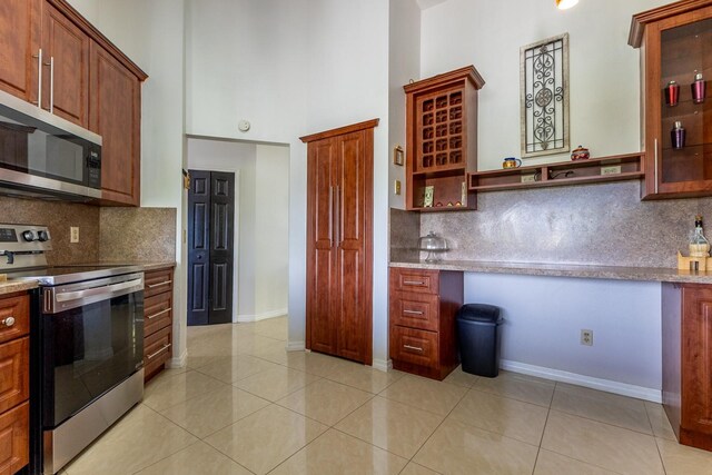 121 White Birch Dr, Kissimmee, FL 34743 - kitchen with stainless steel appliances, backsplash, a towering ceiling, and built in desk