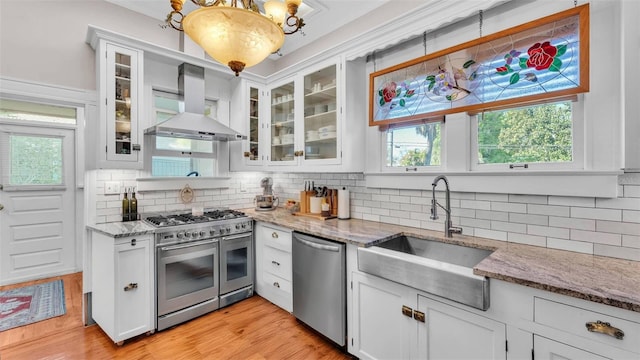 822 W Patterson St, Lakeland, FL 33803 - kitchen with stainless steel appliances, a sink, wall chimney exhaust hood, light wood-style flooring, and decorative backsplash