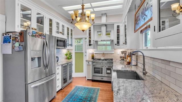 822 W Patterson St, Lakeland, FL 33803 - kitchen featuring stainless steel appliances, wall chimney range hood, a sink, and decorative backsplash