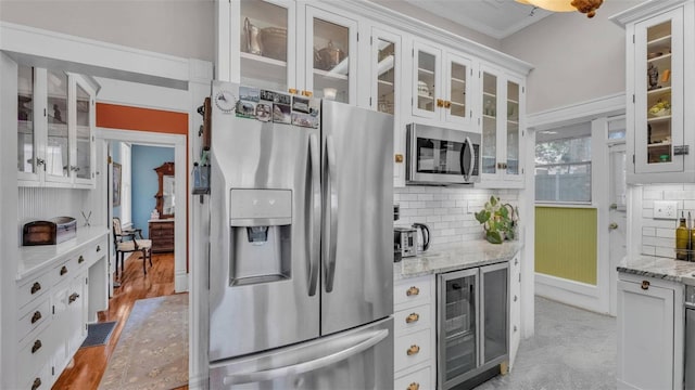 822 W Patterson St, Lakeland, FL 33803 - kitchen featuring appliances with stainless steel finishes, beverage cooler, decorative backsplash, white cabinetry, and light stone countertops