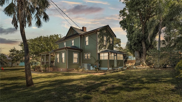 822 W Patterson St, Lakeland, FL 33803 - rear view of house featuring a chimney, a lawn, and a sunroom