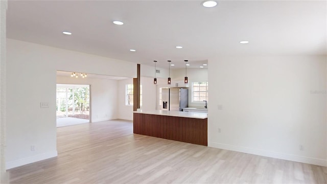 3621 Devonswood Dr, Orlando, FL 32806 - unfurnished living room with light wood-style floors, a sink, baseboards, and recessed lighting