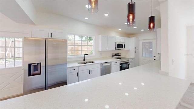 3621 Devonswood Dr, Orlando, FL 32806 - kitchen featuring appliances with stainless steel finishes, a sink, white cabinets, pendant lighting, and vaulted ceiling