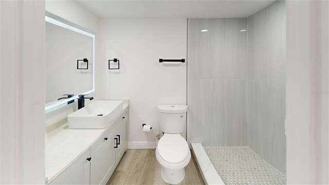 3621 Devonswood Dr, Orlando, FL 32806 - bathroom featuring vanity, toilet, wood finished floors, tiled shower, and baseboards