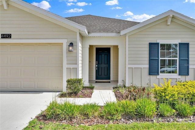 4492 Bluff Oak Loop, Kissimmee, FL 34746 - doorway to property featuring a shingled roof, board and batten siding, an attached garage, and driveway