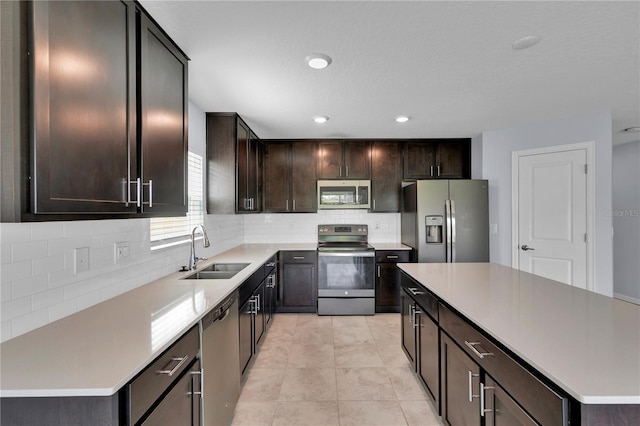 4492 Bluff Oak Loop, Kissimmee, FL 34746 - kitchen with appliances with stainless steel finishes, a sink, decorative backsplash, dark brown cabinets, and a kitchen island